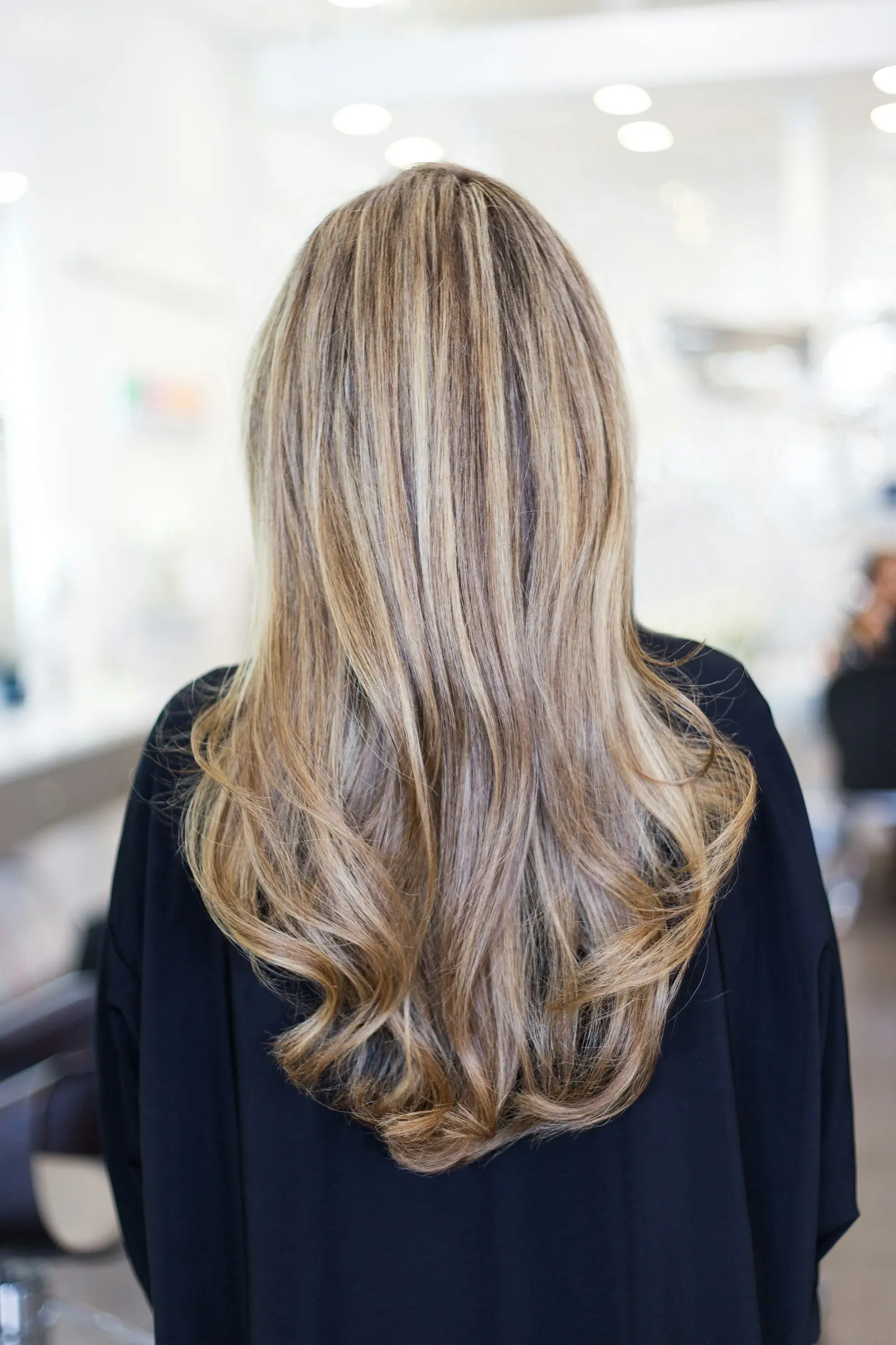 Longs cheveux blonds ondulés, vus de dos, au salon