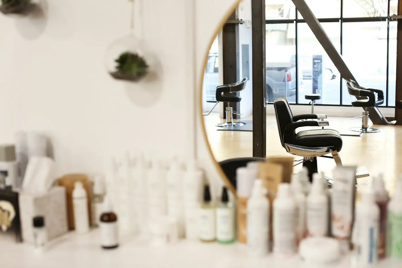 Miroir rond et fauteuil de coiffure près d’une étagère de produits