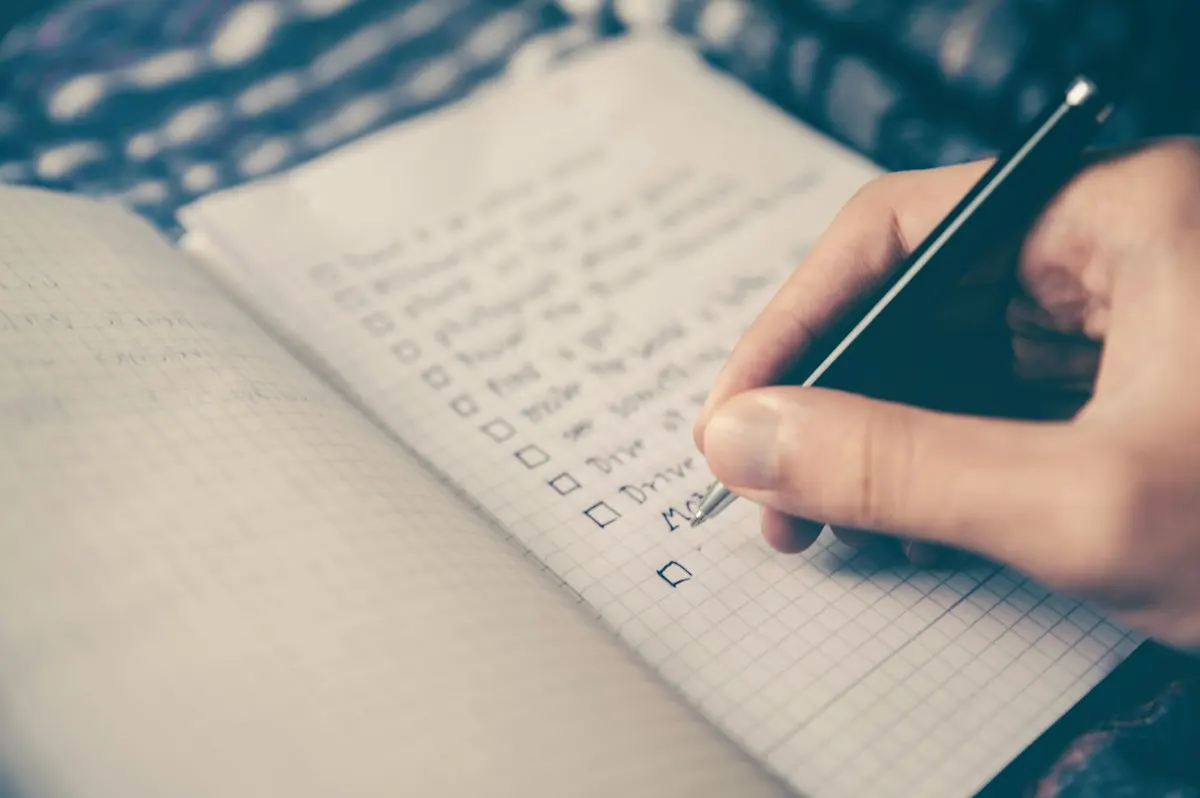 Main cochant une liste dans un carnet