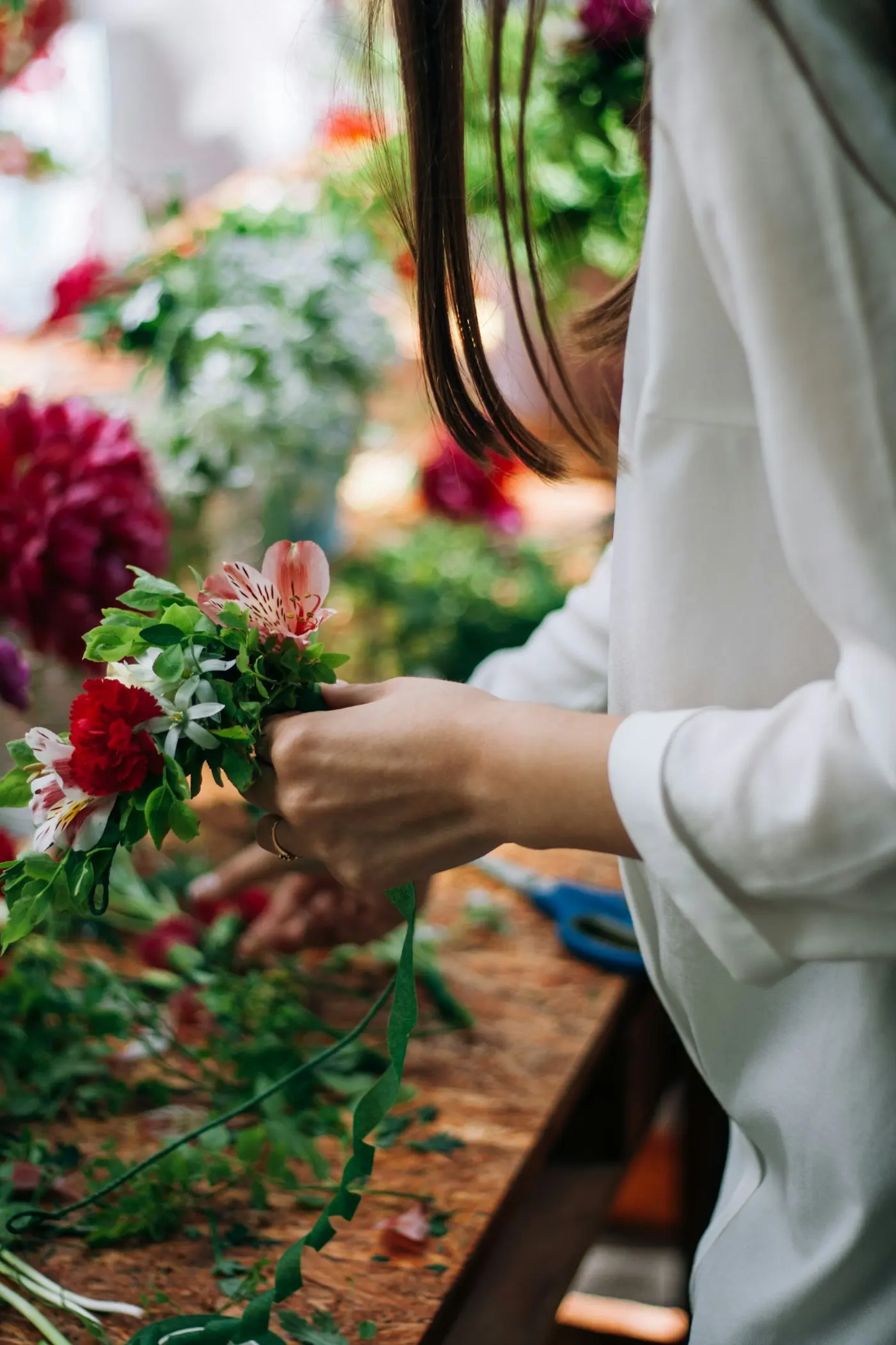 Mains de fleuriste nouant un bouquet à l’atelier