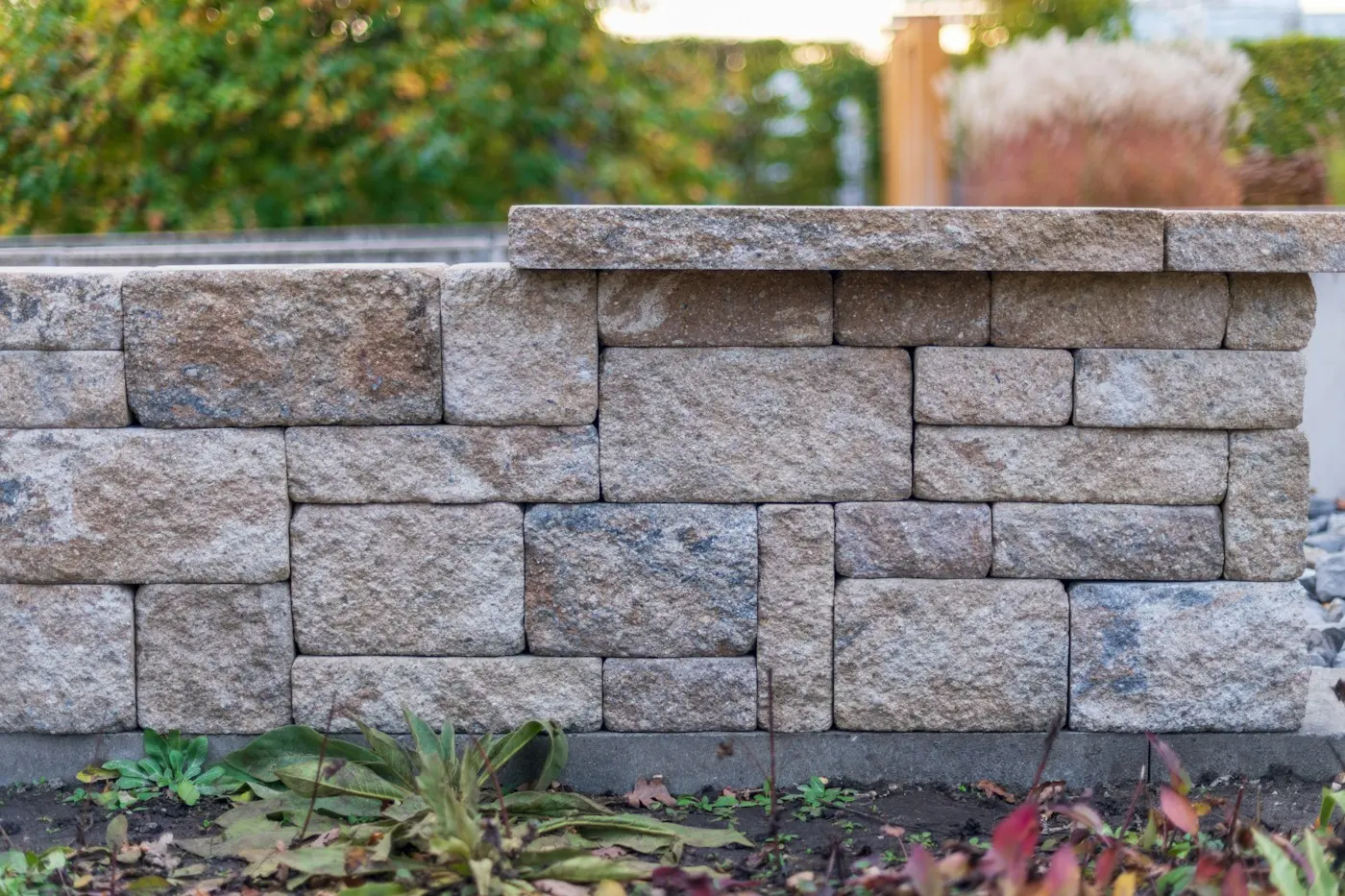 Muret en blocs de pierre au bord d’un jardin