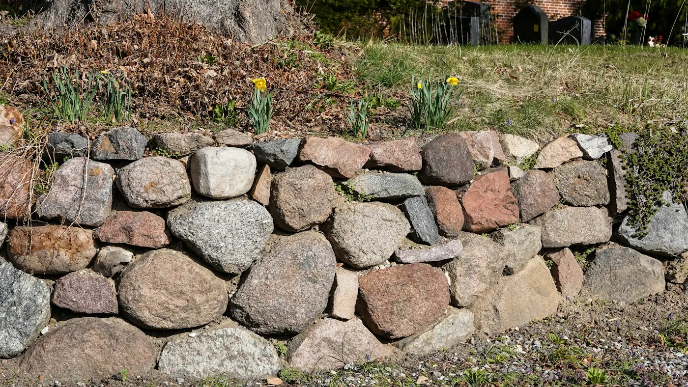 Mur de soutènement en pierre au bord d’un jardin fleuri