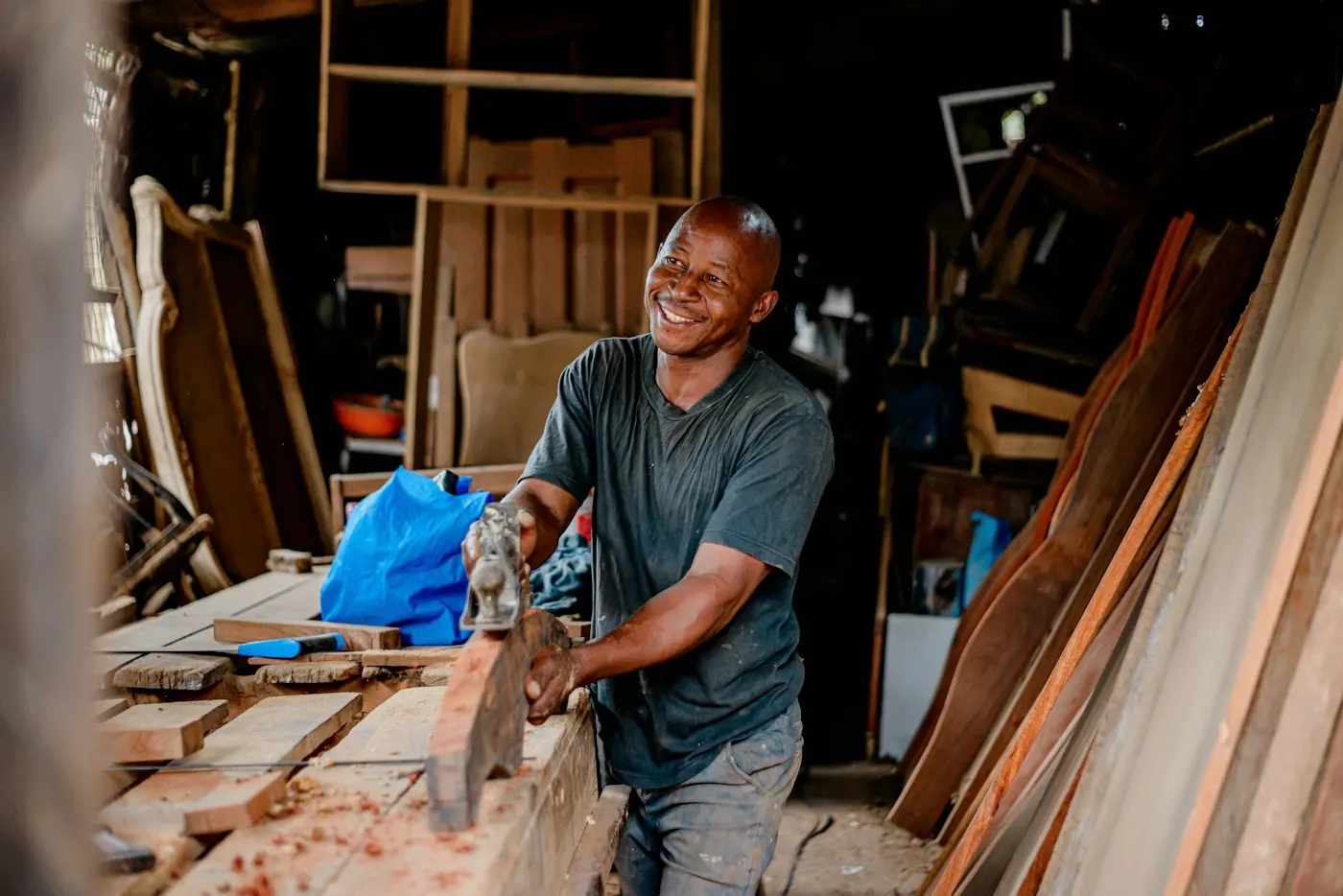Menuisier souriant dans son atelier, planches autour de lui