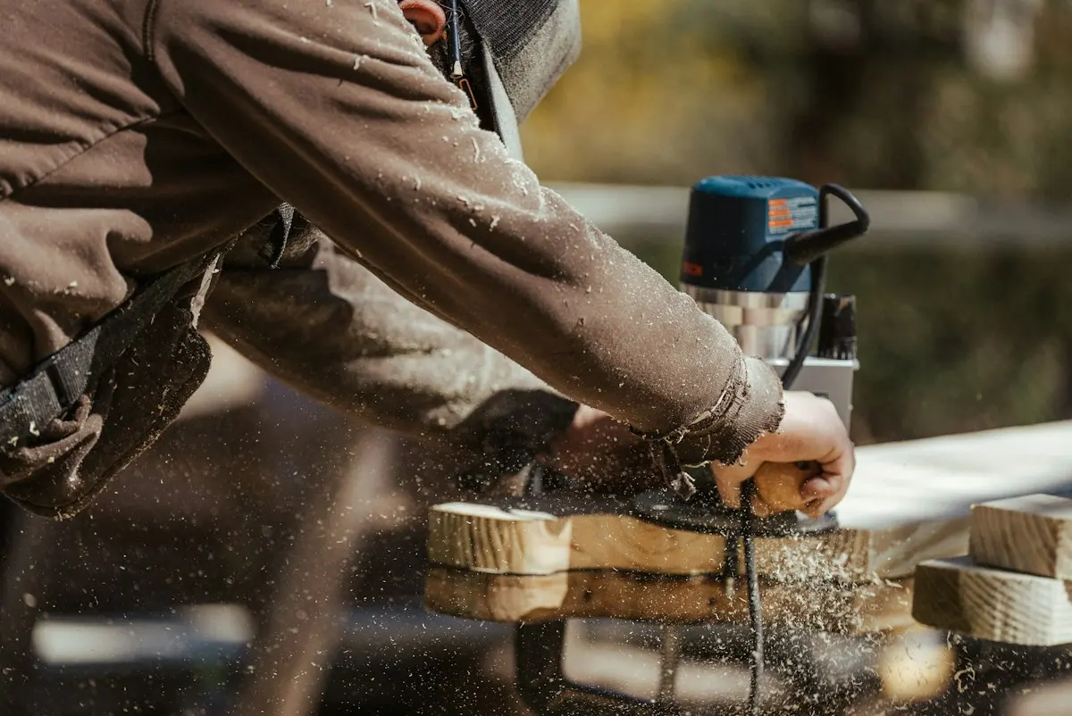 Ponçage d’une pièce de bois, poussière dans la lumière