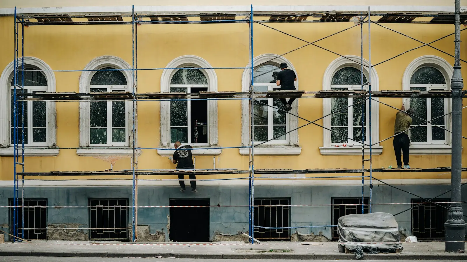 Ouvriers sur un échafaudage devant une façade jaune