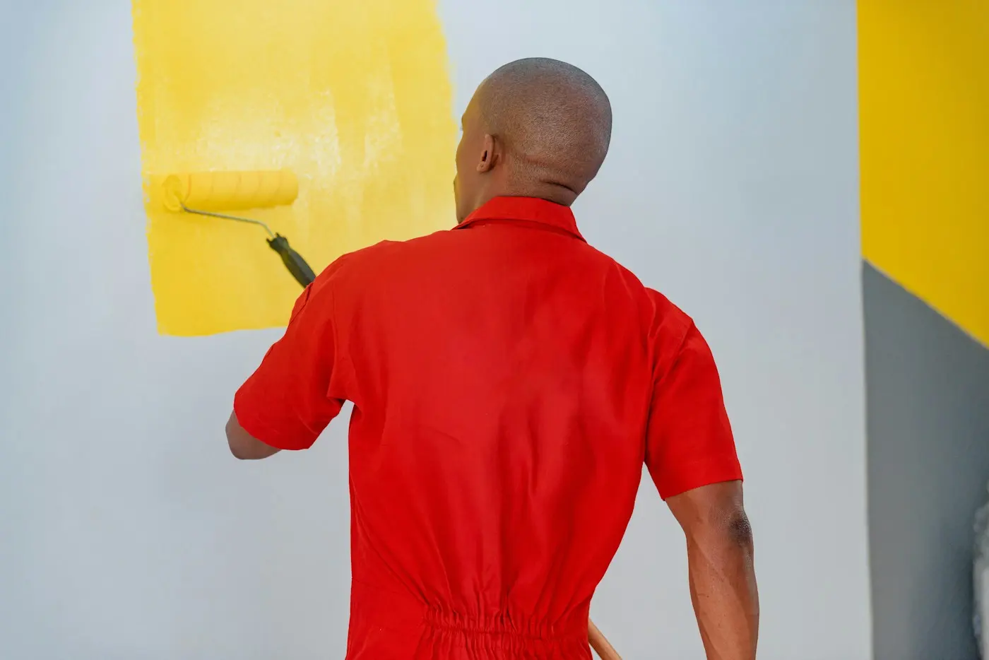 Peintre au rouleau devant un grand aplat jaune