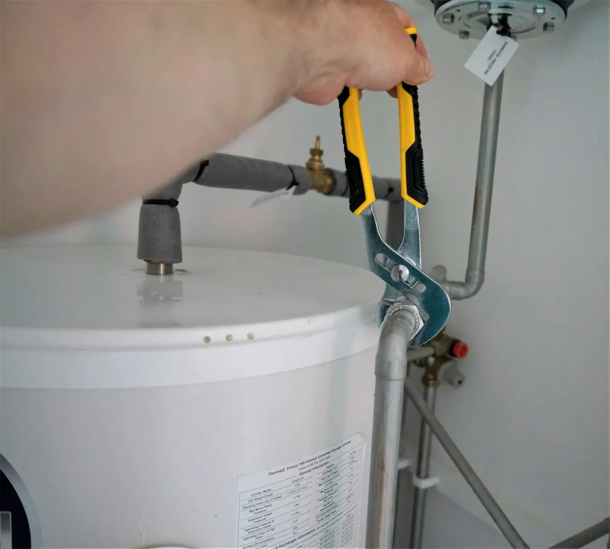 Plombier resserrant un raccord sur un chauffe-eau