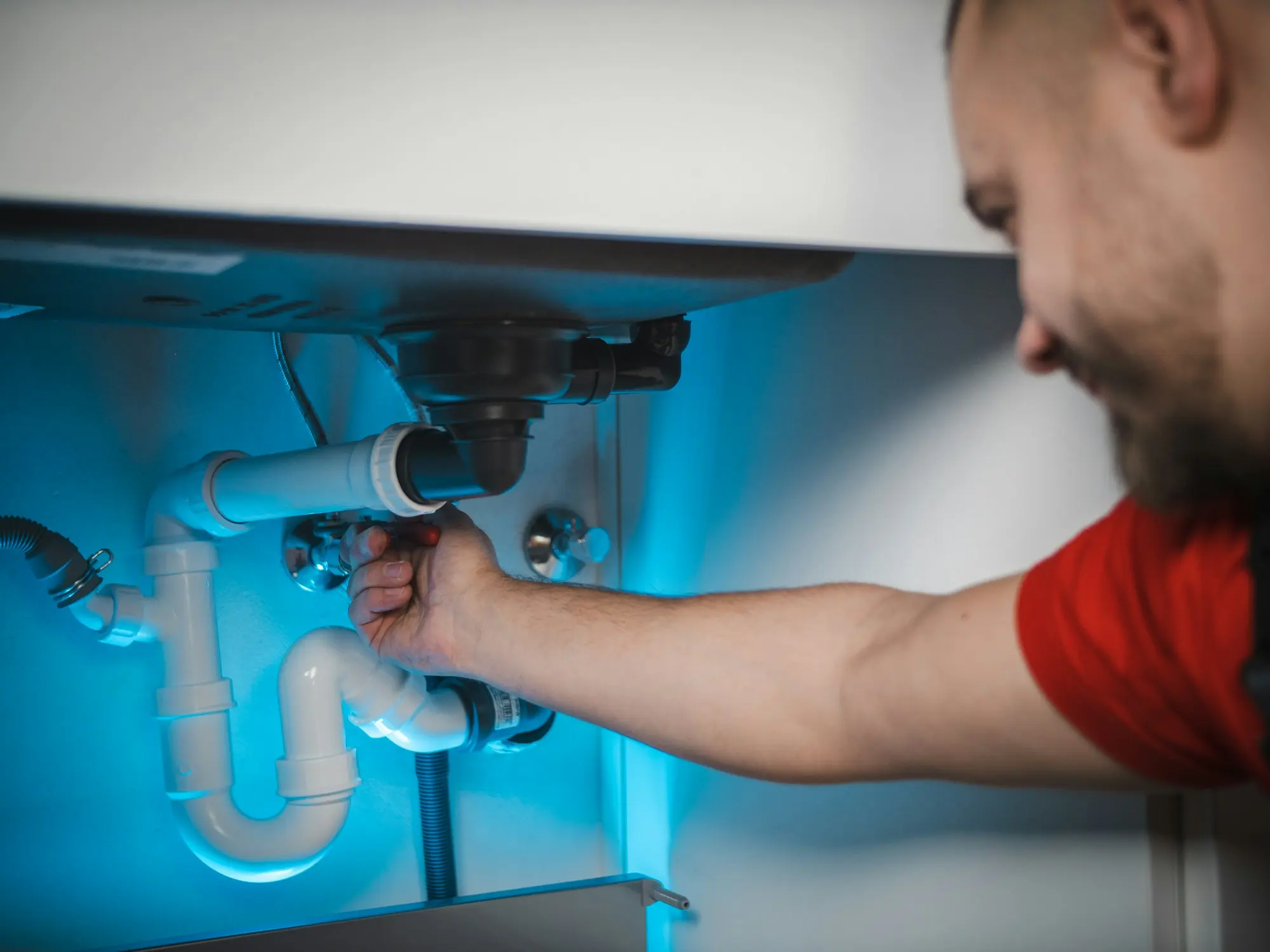 Plombier réparant le siphon sous un évier