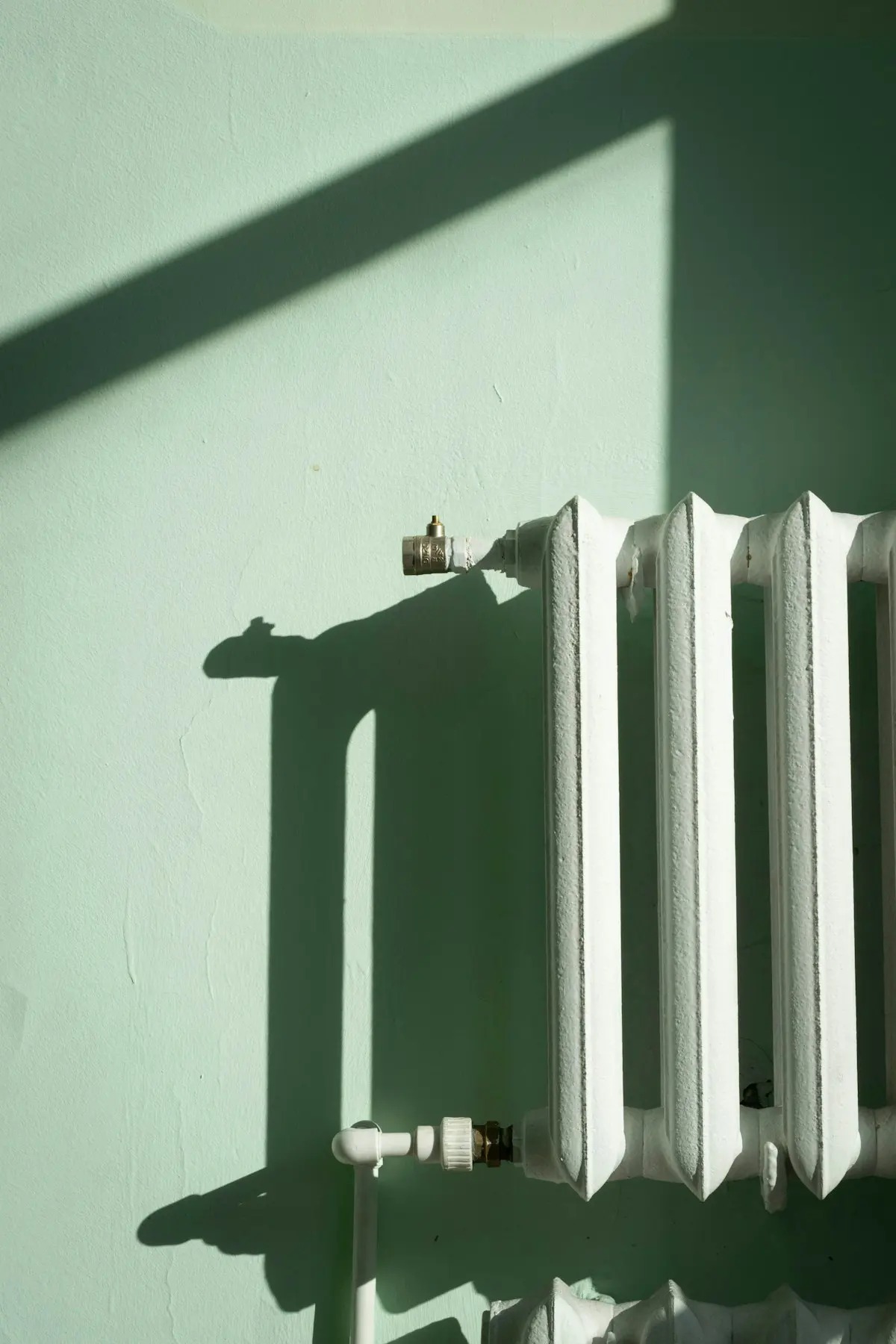 Radiateur en fonte ancien contre un mur vert