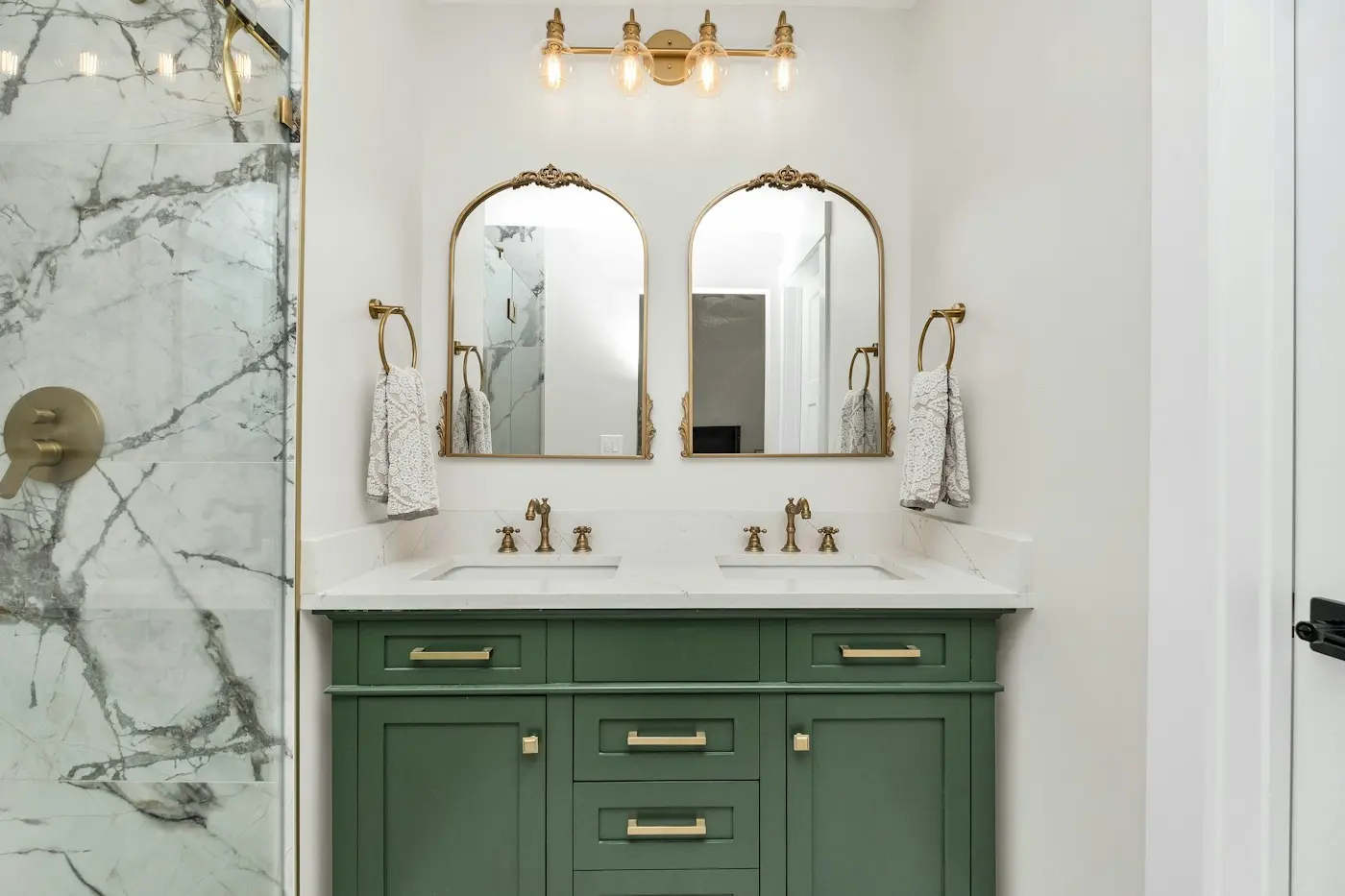 Salle de bain avec meuble vert, marbre et miroirs arrondis