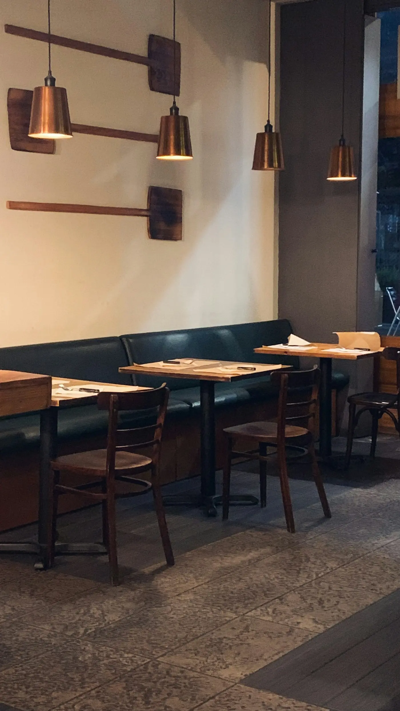 Salle de bistrot avec banquettes vertes et tables en bois