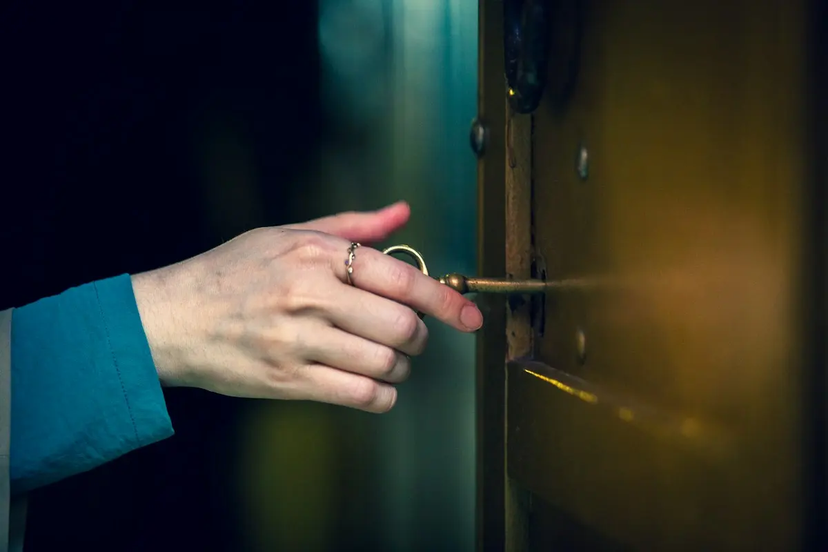 Main introduisant une clé dans la serrure d’une porte sombre