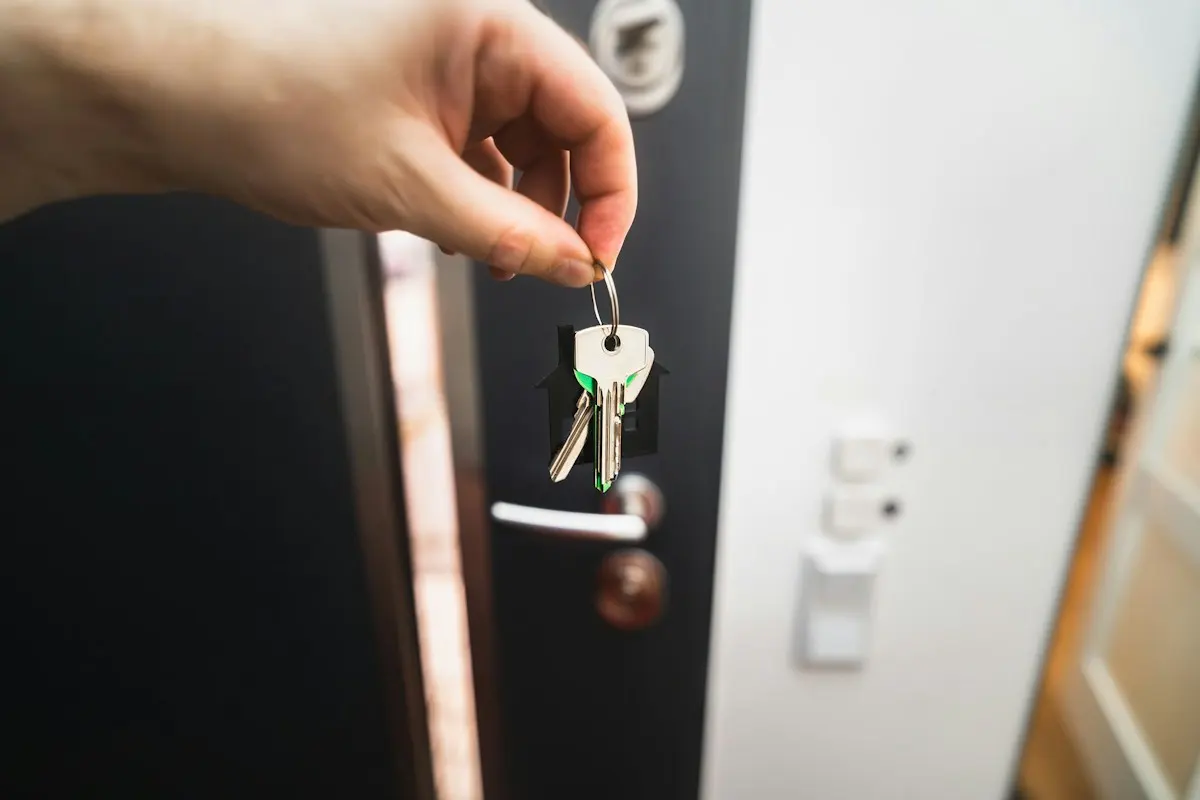 Main tenant un trousseau de clés devant une porte