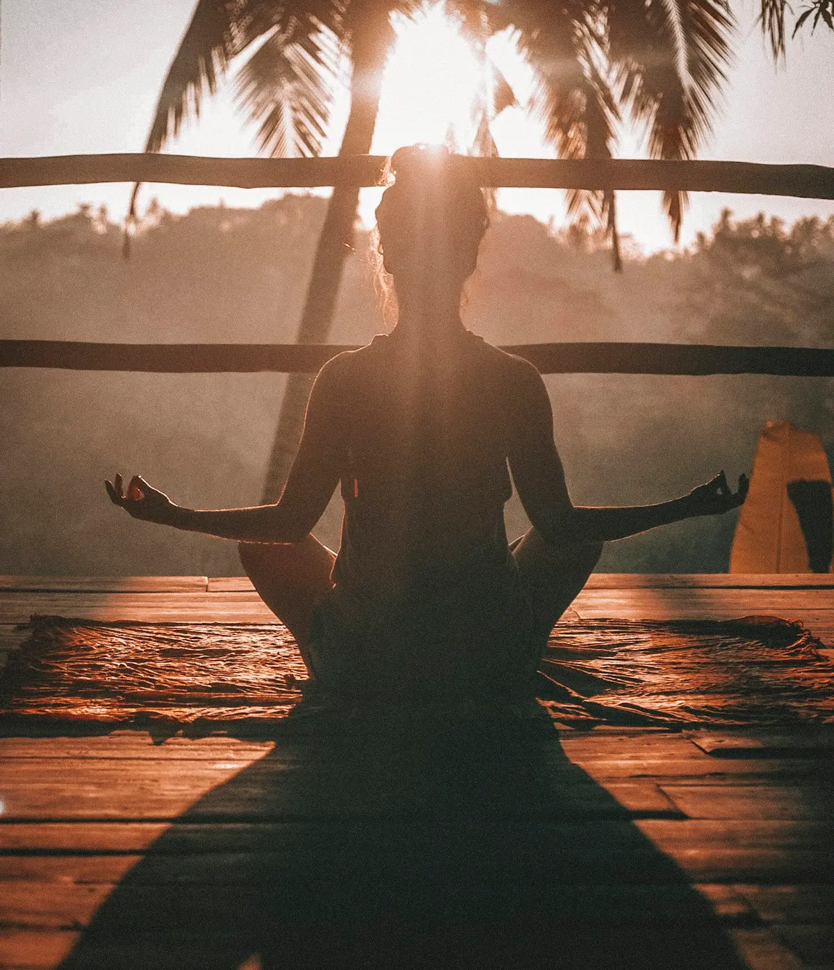 Personne en méditation face à une fenêtre, au coucher du soleil