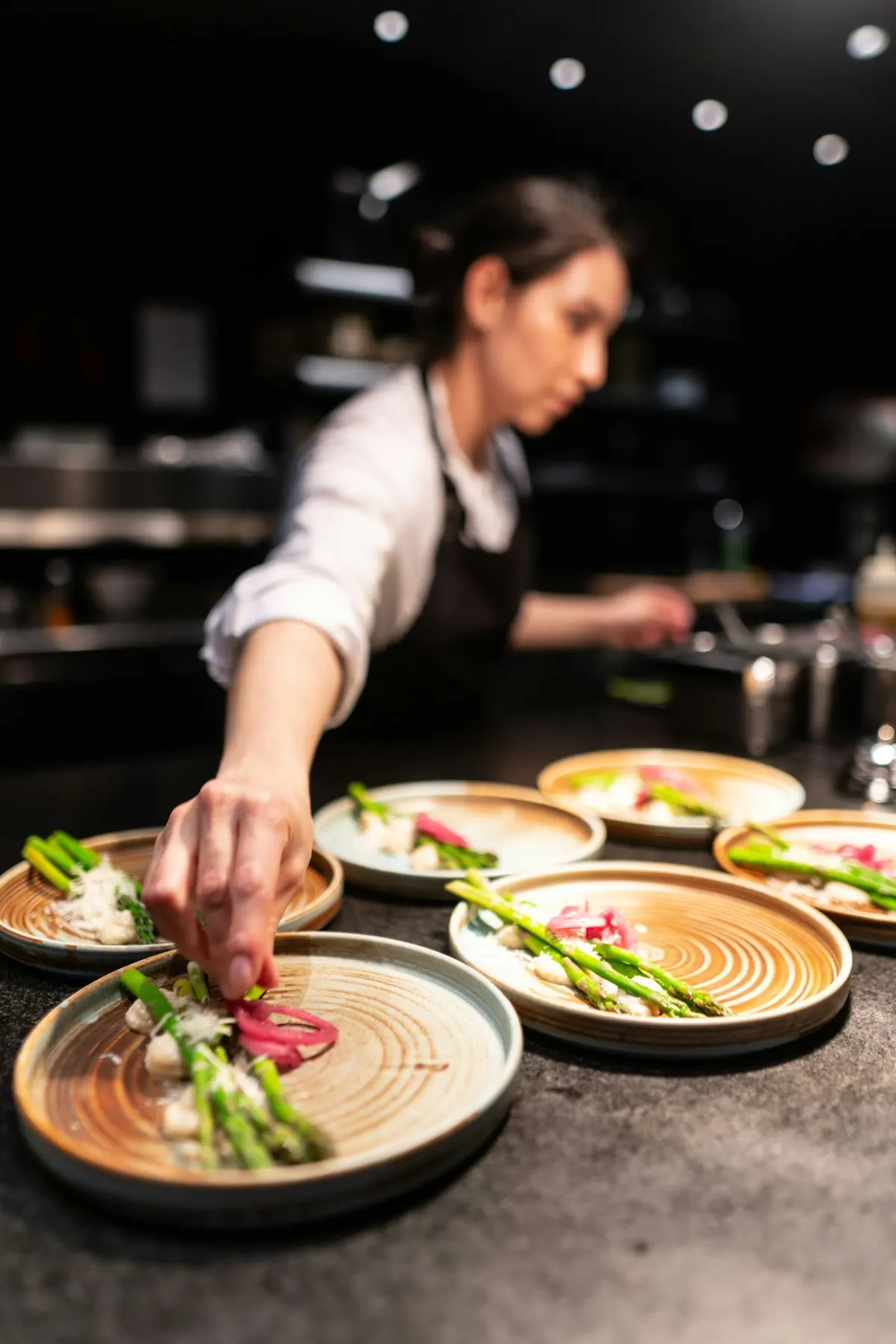 Cuisinière dressant des assiettes au passe