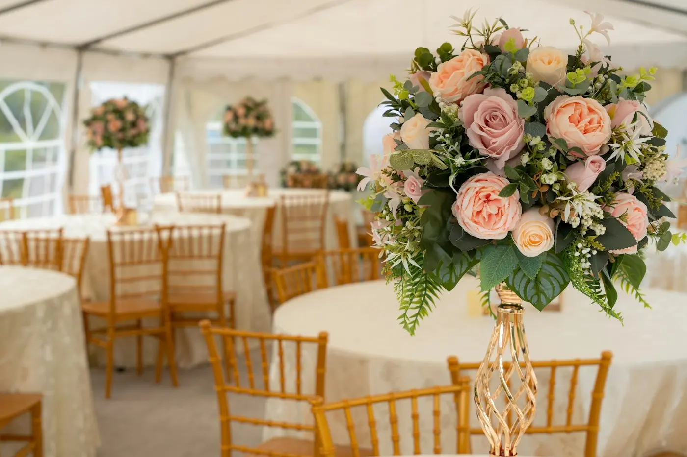 Tables rondes sous une tente, bouquet de roses au premier plan
